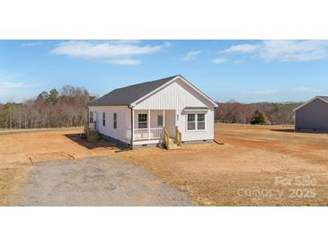 Charming white cottage-style home with a covered front porch and a well-maintained yard in a rural setting at 603 Mt. Wesley Church Rd, Hiddenite, NC 28636