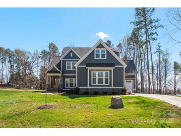 Charming two-story home featuring a well-manicured lawn, architectural shingles, and a seamless side-entry two-car garage at 605 Arrow Point Ln, Davidson, NC 28036