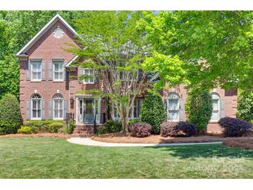 Charming two-story brick home with manicured lawn, mature trees, and inviting front entrance at 6804 Riesman Ln, Charlotte, NC 28210
