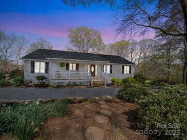 Charming ranch-style home with a welcoming front porch, lush landscaping, and a stone pathway at 925 Lanier Ln, Monroe, NC 28110