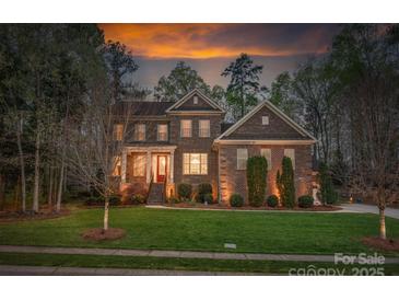 Charming two-story brick home with manicured lawn and mature trees at sunset at 10823 Preservation Park Dr, Charlotte, NC 28214