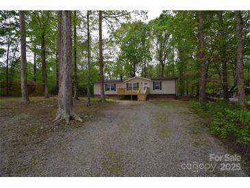 Charming single-story home featuring a front porch, set among beautiful trees, and a spacious gravel driveway at 121 Silver Fox Ct, Mount Holly, NC 28120