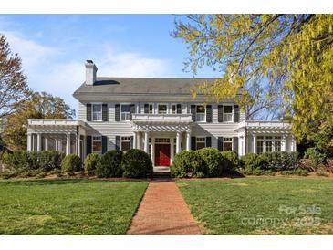 Stately two-story home with a red brick walkway, lush lawn, manicured bushes, and a red front door at 1212 Queens Rd, Charlotte, NC 28207