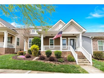 Inviting two-story home showcasing a delightful front porch, picturesque landscaping, and an American flag at 12424 Bradford Park Dr, Davidson, NC 28036