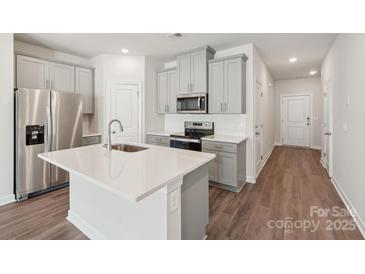 Bright kitchen features stainless steel appliances, gray cabinetry, and a center island with a sink at 1721 Braemar Village Dr, Monroe, NC 28110