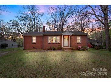 Charming brick home featuring a well-manicured lawn and mature trees against a twilight sky at 304 Simrill Ave, York, SC 29745