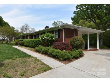 The home features a brick exterior, mature landscaping, and a covered carport at 8608 Cedarbrook Dr, Charlotte, NC 28215