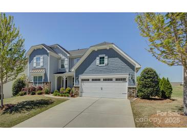 Beautiful two-story home with blue siding, white trim, a two-car garage, and a well-manicured front lawn at 16524 Palisades Commons Dr, Charlotte, NC 28278