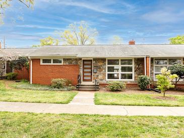 Charming single-story home with a stone facade, brick accents, a modern wood door, and a well-manicured lawn at 4625 Woodlark Ln, Charlotte, NC 28211