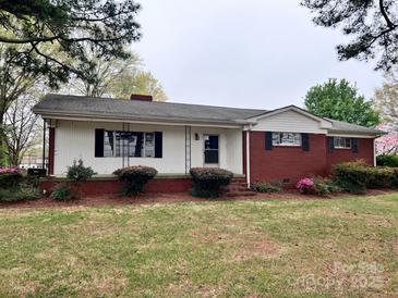 Charming single-story home featuring a brick and white siding exterior with a cozy front porch and landscaped yard at 511 W Main St, Cleveland, NC 27013