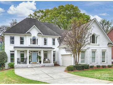 Stunning white brick home featuring a well-manicured lawn and attached two-car garage at 6225 Woodleigh Oaks Dr, Charlotte, NC 28226