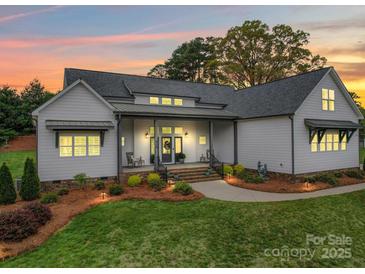 Beautiful home exterior with manicured lawn, landscaping, and a charming covered front porch at sunset at 630 Deese Rd, Monroe, NC 28110