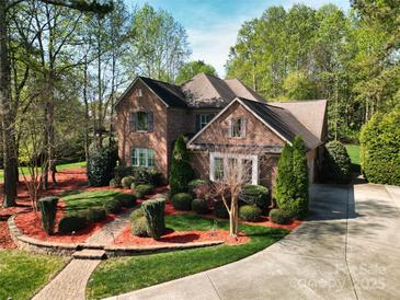 Charming brick home featuring mature landscaping, a winding walkway, and a concrete driveway at 13620 Castleford Dr, Mint Hill, NC 28227