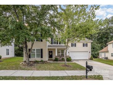 Two-story home with mature trees, covered porch, and a driveway leading to a two-car garage at 3009 Early Rise Ave, Indian Trail, NC 28079