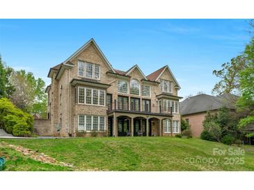 Expansive brick home with a covered porch and balcony overlooking a well-maintained lawn at 4300 Old Course Dr, Charlotte, NC 28277