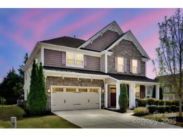 Charming two-story home featuring a stone facade, two-car garage, and well-manicured landscaping at 704 Fresia Dr, Tega Cay, SC 29708