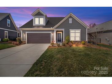 Charming single-Gathering home featuring a manicured lawn, gray siding, and a two-car garage at dusk at 9087 Treetop Nw Way, Concord, NC 28027