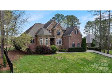 Beautiful two-story home featuring stone and brick, mature landscaping, and a well-manicured lawn at 116 Whispering Cove Ct, Mooresville, NC 28117