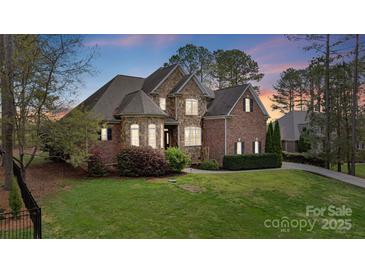 Charming two-story brick and stone home with lush landscaping and a well-manicured lawn at 116 Whispering Cove Ct, Mooresville, NC 28117