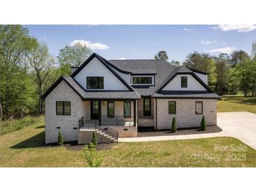 Charming two-story home with light brick, black trim, a covered porch, and a manicured lawn at 3500 Manna Ln, Mount Holly, NC 28120