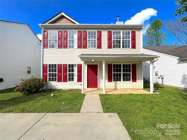 Inviting two-story home featuring a well-manicured lawn, red shutters, and a charming front porch at 7147 Henderson Valley Ln, Charlotte, NC 28269