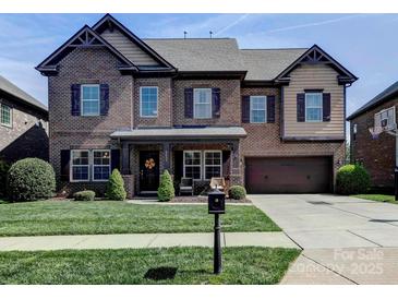 Charming two-story brick home with a well-manicured lawn, attached garage, and inviting front porch at 9622 Harvest Pond Nw Dr, Concord, NC 28027