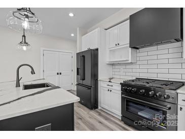 Modern kitchen with white cabinets, black appliances, stylish countertops and wood floors at 143 Mills Garden Rd, Statesville, NC 28625