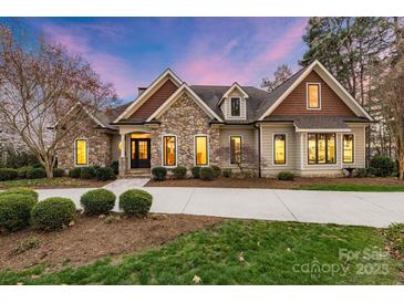 Charming stone and siding home with a well-manicured lawn and a long, curved driveway at 239 Paradise Peninsula Rd, Mooresville, NC 28117