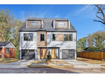 Modern duplex featuring light gray siding, two garage doors, wooden accents and a blue sky at 3129 Rush Ave, Charlotte, NC 28208