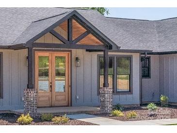 Charming home showcasing a stylish front door with a covered entrance and meticulously maintained landscaping at 32519 Buchanan Ln, Albemarle, NC 28001