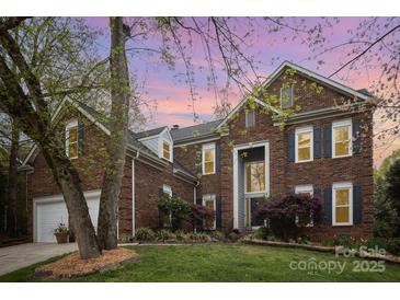 Elegant brick home with dark shutters, lush landscaping, and a well-manicured lawn under a vibrant dusk sky at 3409 Pondview Ln, Charlotte, NC 28210