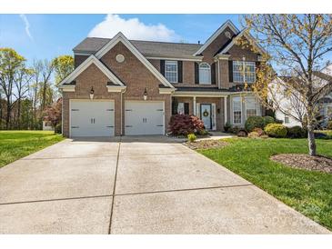 Charming brick two-story home with attached two car garage and a well-manicured lawn at 5854 Crimson Oak Ct, Harrisburg, NC 28075