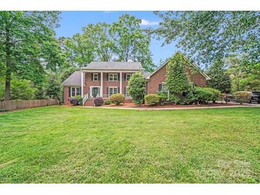 Traditional two-story brick home with a lush green lawn and mature trees providing ample shade at 6730 Gold Wagon Ln, Mint Hill, NC 28227
