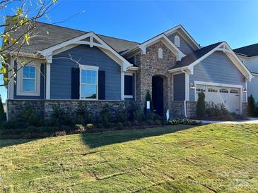 Charming home with a stone facade, blue siding, a well-manicured lawn, and a two-car garage at 1468 Honey Trl, Monroe, NC 28112