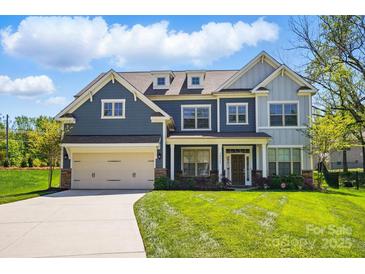 Charming two-story home with a manicured lawn, a two-car garage, and beautiful blue and grey siding at 20422 Creek Bend Edge Ct, Matthews, NC 28105