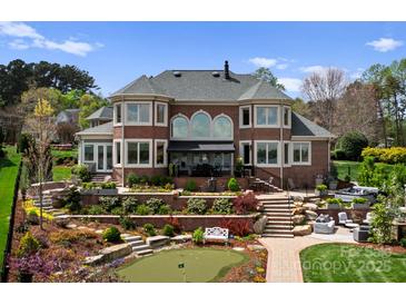 Expansive backyard with stone terracing, putting green, and an outdoor living area, perfect for entertaining at 3988 Channel Point Ln, Denver, NC 28037