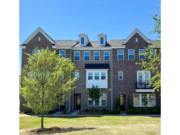 Charming brick townhome featuring dormer windows, a well-manicured lawn, and verdant landscaping at 7957 Reunion Row Dr, Charlotte, NC 28277