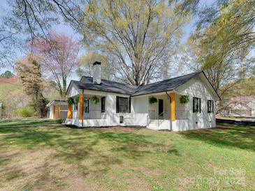 Charming exterior view of a white home featuring a black roof, front porch and landscaped yard at 1209 Mount Ulla Hwy, Mooresville, NC 28115
