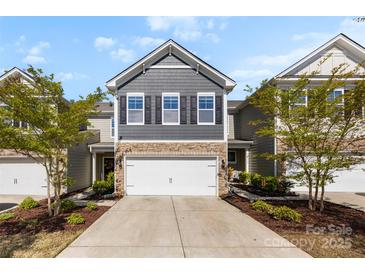 Charming townhome featuring stone accents, gray siding, a two-car garage, and manicured landscaping at 1212 Croft Dr, Fort Mill, SC 29708
