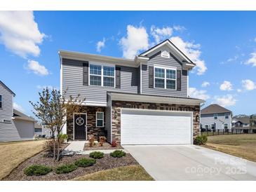 Charming two-story home features gray siding, stone accents, a two-car garage and a welcoming front door at 15122 Lake Ridge Rd, Charlotte, NC 28278
