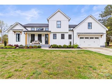 Charming two-story modern farmhouse exterior with black trimmed windows and attached two-car garage at 211 Killian Rd, Stanley, NC 28164