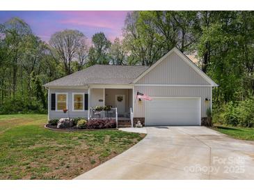 Charming single-story home featuring a welcoming front porch and a well-maintained front yard with an attached garage at 2402 Winfield St, Kannapolis, NC 28083