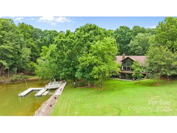 Lakefront home featuring a private dock, lush greenery, and well-maintained lawn at 307 Stillwater Rd, Troutman, NC 28166
