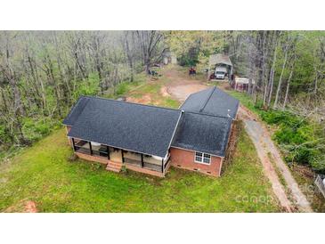 Aerial view of a red brick home with a covered front porch and black roof, surrounded by a green lawn at 3720 Lanes Creek Rd, Marshville, NC 28103