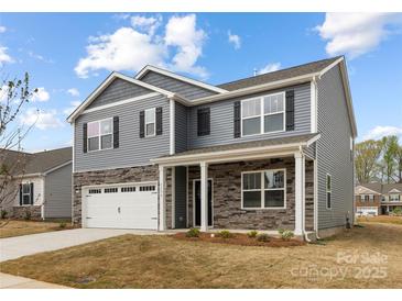 Charming two-story home with gray siding, stone accents, covered porch and two car garage at 7730 Woolsey Dr, Gastonia, NC 28056