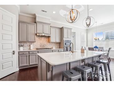 Beautiful kitchen boasts gray cabinets, quartz countertops, stainless steel appliances, and a central island at 15402 Country Lake Dr, Pineville, NC 28134