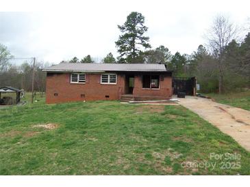 Exterior view of a single-story brick home featuring a metal roof and a spacious front yard at 1842 Quail Run Dr, Kingstown, NC 28150