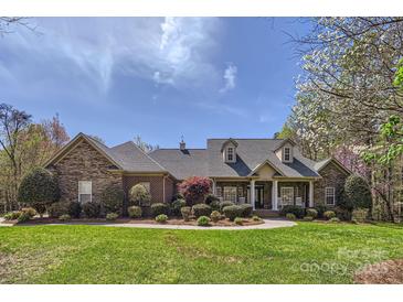 Beautiful stone and brick home with a manicured lawn, mature trees, and covered porch at 310 Frontier Cir, Indian Trail, NC 28079