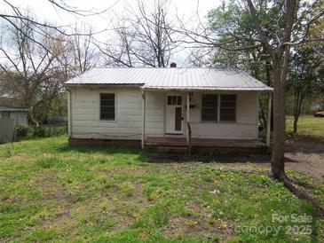 Modest single-story home featuring metal roof and mature trees in front yard at 605 W Elm St, Shelby, NC 28150