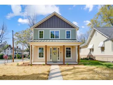 Charming two-story home featuring a covered front porch with wooden columns and a light green front door at 68 Cabarrus W Ave, Concord, NC 28025